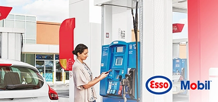 Photo of woman at gas station fuel dispenser, with Esso and Mobil logos