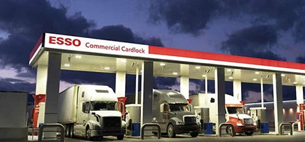 Photo of transport trucks parked under Esso cardlock canopy at night
