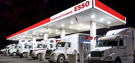 Photo de camions de transport garés sous le auvent de la station-service Esso la nuit
